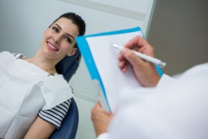 Palavra chave: Proservação Título SEO: Proservação odontológica: guia para dentistas Meta-descrição: Entenda como realizar a Proservação na clínica odontológica e quais cuidados o dentista deve ter no acompanhamento dos pacientes. Proservação: conduta do dentista na clínica odontológica A Proservação é uma etapa importante da prática odontológica, especialmente após tratamentos que exigem acompanhamento clínico e radiográfico ao longo do tempo. Mais do que verificar se o procedimento foi concluído, essa conduta permite ao dentista avaliar a evolução do caso, identificar possíveis alterações e tomar decisões terapêuticas de maneira preventiva. Por isso, estabelecer uma rotina de acompanhamento é fundamental para oferecer um atendimento mais seguro e previsível. Na clínica odontológica, a proservação deve ser planejada de acordo com o procedimento realizado, as características do paciente e os objetivos do tratamento. Isso significa que não existe um único protocolo aplicável a todos os casos. Mas, afinal, como o dentista deve conduzir esse acompanhamento? Neste artigo, vamos explicar os principais pontos que devem fazer parte da rotina de proservação odontológica. O que é proservação na odontologia? A proservação consiste no acompanhamento periódico do paciente após a realização de um tratamento odontológico, com o objetivo de verificar sua evolução e identificar possíveis alterações. Ela pode envolver avaliação clínica, exames de imagem, comparação com registros anteriores e análise dos sintomas relatados pelo paciente. Dessa forma, o acompanhamento não se limita à observação de uma única consulta: ele considera a evolução do quadro ao longo do tempo. A necessidade de proservação pode estar presente em diferentes áreas da odontologia. Tratamentos endodônticos, cirurgias, implantes, procedimentos periodontais e determinadas intervenções restauradoras, por exemplo, podem demandar acompanhamento específico. O período e a frequência das consultas devem ser definidos pelo cirurgião-dentista conforme as particularidades de cada caso. Proservação: qual deve ser a conduta do dentista? Para realizar uma proservação adequada, o dentista deve estabelecer critérios objetivos para acompanhar a evolução do tratamento. Embora a conduta possa variar, alguns passos são importantes. 1. Registrar as informações do tratamento O primeiro passo é manter um prontuário odontológico completo e atualizado. Informações como diagnóstico, procedimento realizado, materiais utilizados, exames complementares e observações clínicas ajudam a construir um histórico do caso. Registros de exames de imagem também são importantes, pois permitem realizar comparações futuras e identificar mudanças que poderiam passar despercebidas quando um exame é analisado de maneira isolada. Uma documentação organizada facilita tanto o acompanhamento quanto a tomada de decisão clínica. 2. Definir o período de acompanhamento O intervalo entre as consultas de retorno não deve ser estabelecido de maneira aleatória. O dentista precisa considerar o tipo de tratamento, a resposta apresentada pelo paciente e os objetivos da avaliação. Em determinados casos, pode ser necessário um acompanhamento mais próximo. Em outros, os retornos podem ocorrer em intervalos maiores. Por isso, ao finalizar o tratamento, é importante orientar o paciente sobre a necessidade de retornar à clínica e explicar por que esse acompanhamento faz parte do cuidado odontológico. 3. Realizar uma avaliação clínica detalhada Durante a consulta de proservação, o profissional deve verificar a condição clínica da região tratada e investigar possíveis sinais ou sintomas. Dependendo do caso, podem ser avaliados aspectos como: Presença ou ausência de dor; Sensibilidade; Edema ou alterações nos tecidos; Mobilidade dentária; Condição periodontal; Integridade de restaurações ou próteses; Função e conforto do paciente; Sinais de recorrência ou progressão da alteração inicialmente diagnosticada. Além disso, é importante comparar os achados atuais com as informações registradas durante as etapas anteriores do tratamento. A importância dos exames de imagem na proservação Os exames de imagem podem ter um papel fundamental na Proservação, principalmente quando é necessário acompanhar estruturas que não podem ser avaliadas apenas clinicamente. Radiografias odontológicas, por exemplo, podem auxiliar na análise da evolução de determinadas condições e na comparação entre exames realizados em diferentes momentos. Em situações mais complexas, a tomografia computadorizada de feixe cônico (TCFC) pode fornecer informações tridimensionais importantes para a avaliação de estruturas dentomaxilofaciais. Entretanto, a indicação do exame deve ser baseada na necessidade clínica. O objetivo não é solicitar exames de maneira indiscriminada, mas utilizar os recursos disponíveis quando eles puderem contribuir efetivamente para a avaliação do caso. Outro ponto importante é buscar, sempre que possível, padronização na aquisição e comparação das imagens. Isso favorece uma análise mais consistente da evolução observada ao longo do tempo. Como interpretar a evolução do tratamento? A proservação não deve ser entendida simplesmente como uma consulta para confirmar se “está tudo bem”. O dentista precisa analisar os resultados considerando o diagnóstico inicial, o tratamento realizado e a evolução esperada. Quando existem exames anteriores, a comparação pode ser especialmente útil. Uma alteração que parece discreta em uma imagem isolada pode apresentar maior significado quando analisada em conjunto com exames prévios. Da mesma forma, a ausência de sintomas não necessariamente significa que não exista nenhuma alteração. Dependendo do tratamento e da condição avaliada, mudanças clínicas e radiográficas podem seguir ritmos diferentes. Por isso, a decisão deve considerar o conjunto de informações clínicas e imaginológicas, evitando conclusões baseadas em apenas um indicador. O que fazer quando são identificadas alterações? Caso a proservação indique alguma alteração, o dentista deve avaliar sua relevância clínica e determinar a necessidade de intervenção. A conduta pode incluir apenas a continuidade do acompanhamento, a solicitação de exames complementares, ajustes no tratamento ou a realização de uma nova intervenção, dependendo do diagnóstico. Também pode ser necessário encaminhar o paciente para outro especialista quando o caso exigir uma avaliação mais específica. O mais importante é evitar decisões automáticas. Cada situação deve ser analisada individualmente, considerando riscos, benefícios, prognóstico e condições gerais do paciente. Orientação ao paciente também faz parte da proservação A participação do paciente é outro componente importante do acompanhamento. Durante a consulta, o dentista deve explicar o resultado da avaliação e reforçar a importância dos retornos programados. Também é importante orientar sobre sinais que devem motivar uma nova consulta antes do período inicialmente previsto, como dor persistente, aumento de volume, alterações funcionais ou outras mudanças percebidas pelo próprio paciente. Essa comunicação contribui para melhorar a adesão ao acompanhamento e permite que possíveis intercorrências sejam investigadas de maneira mais precoce. Proservação como parte do planejamento odontológico Quando incorporada à rotina clínica, a Proservação deixa de ser uma etapa secundária e passa a integrar o próprio planejamento do tratamento. Definir previamente como o caso será acompanhado, quais parâmetros serão avaliados e quando novos exames poderão ser necessários ajuda o dentista a organizar o atendimento e acompanhar a evolução com maior segurança. Além disso, manter registros clínicos e exames de imagem adequadamente arquivados cria um histórico que pode ser consultado ao longo dos anos, contribuindo para decisões futuras. A importância de uma avaliação baseada em acompanhamento A proservação permite que o dentista acompanhe o paciente para além do momento em que o procedimento é concluído. Com avaliação clínica, documentação adequada e exames de imagem quando indicados, o profissional consegue observar a evolução do caso e identificar alterações que podem exigir novas condutas. Para o cirurgião-dentista, portanto, estabelecer uma rotina de proservação é uma maneira de tornar o acompanhamento mais organizado e baseado na evolução real de cada paciente. Proservação-1