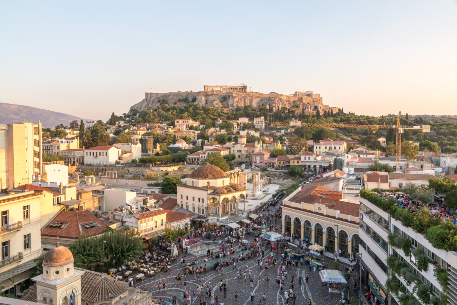Elevated view of Monastiraki square crowded with tourists and the Acropolis at sunset. Athens, Greece, Europe