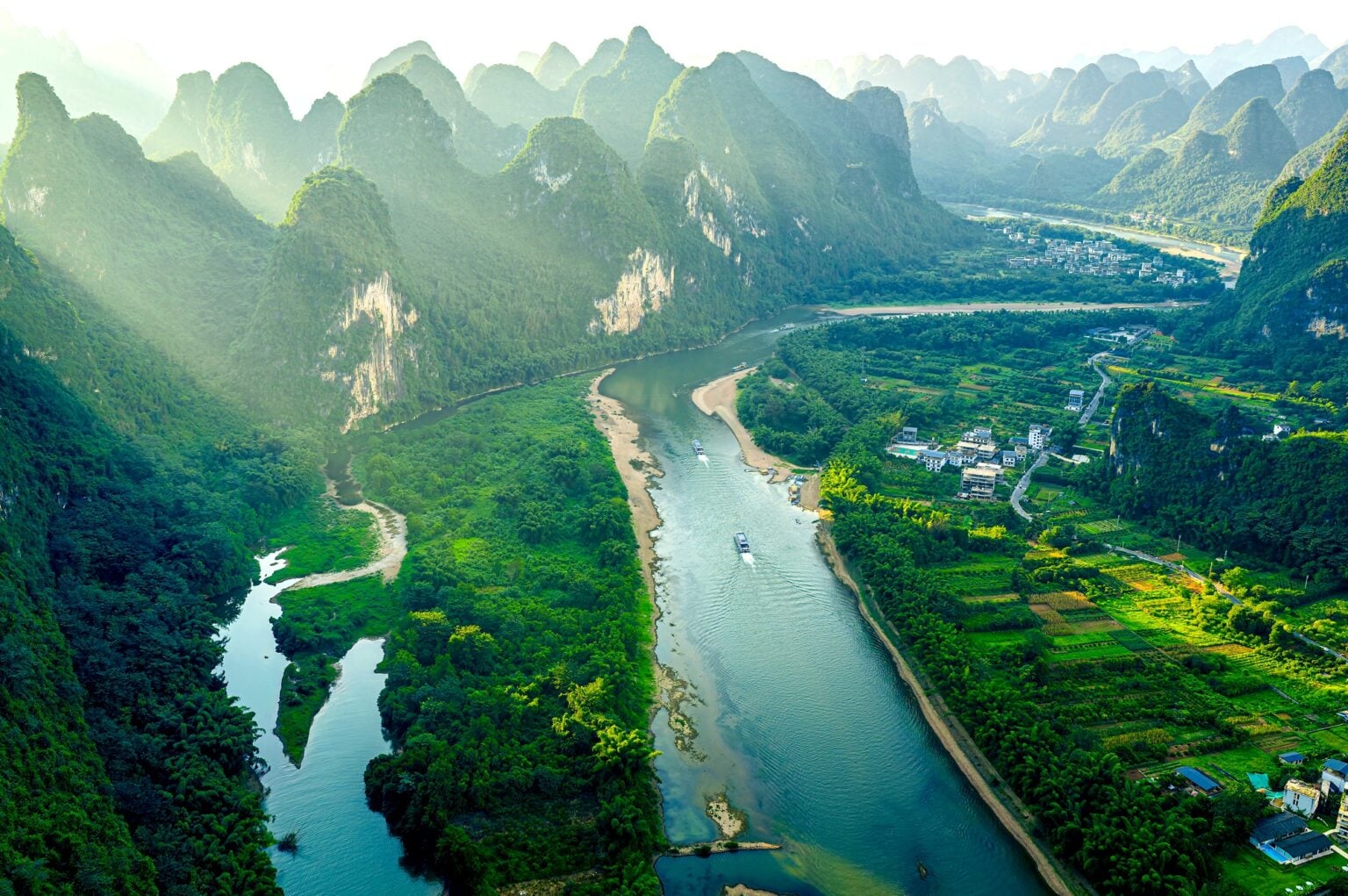 Breathtaking view of Li River winding through karst mountains with boats at sunrise in Guilin, China.