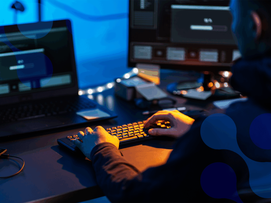 Pessoa realizando uma invasão cibernética em um computador, com múltiplos monitores exibindo códigos e gráficos de segurança digital.