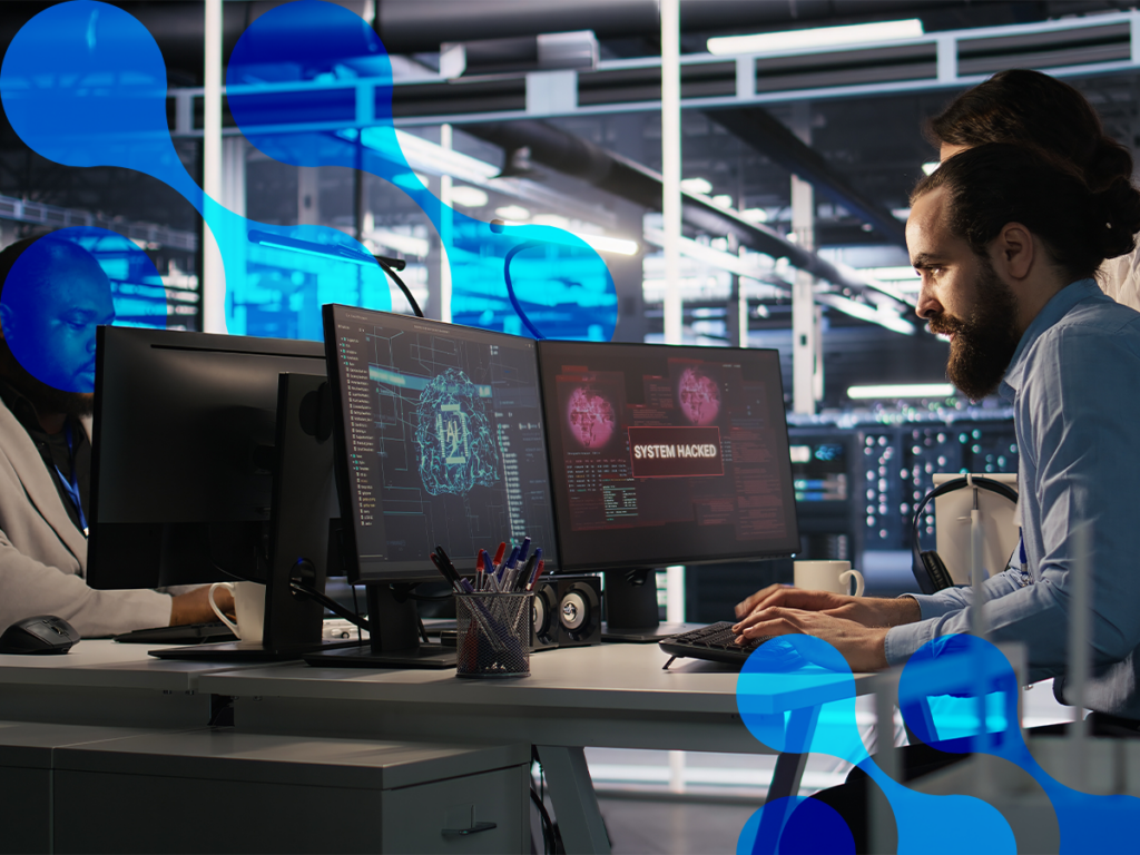 Profissional observa telas de computadores que indicam um ataque feito e a necessidade de proteção contra ramsonware